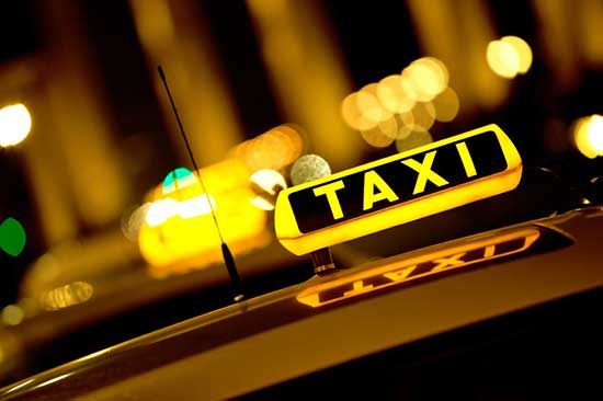 A "TAXI" sign with its light on, indicating it is available